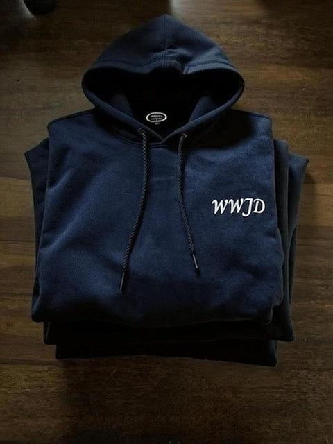 Folded navy blue hoodie with 'WWJD' text on a wooden surface